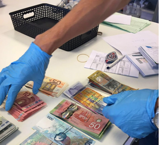 Investigators from the Netherlands count money seized during a search. Investigators from the Netherlands count money seized during a search.